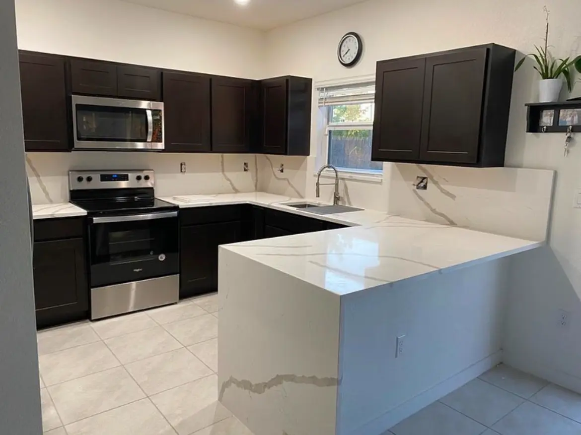 White quartz peninsula with waterfall end and dark cabinetry